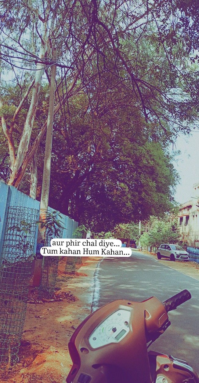 a scooter parked on the side of a road next to a fence and trees