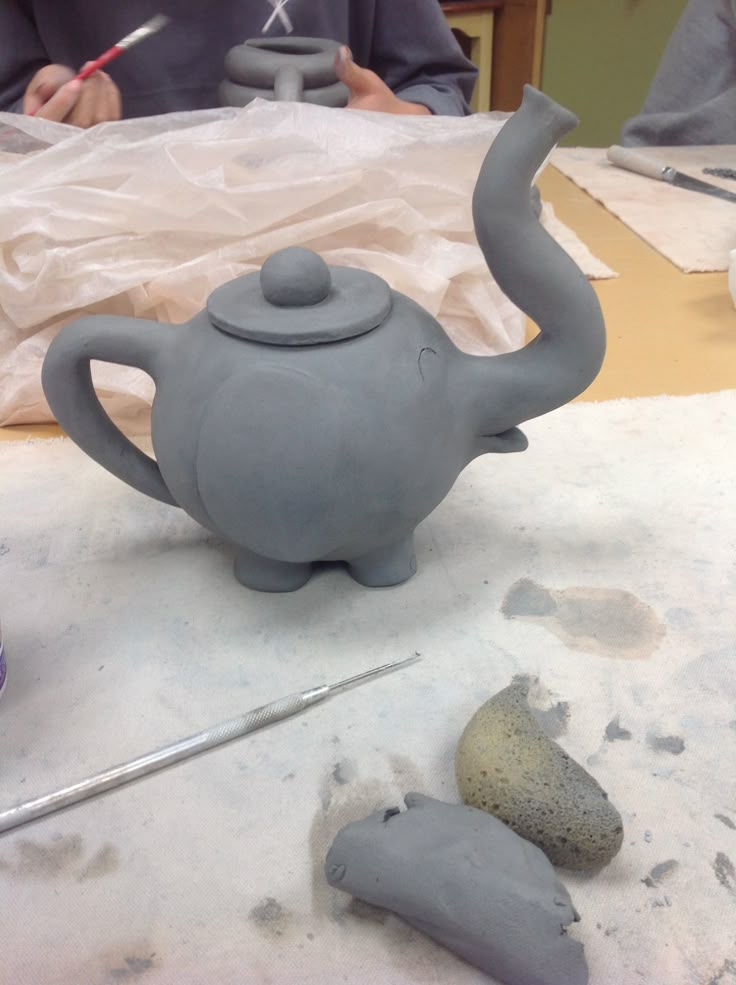 an elephant teapot sitting on top of a table next to a rock and some scissors