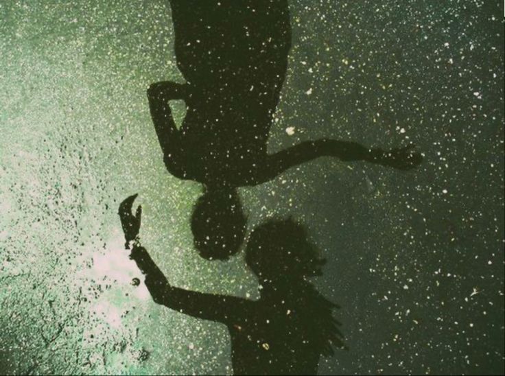 the shadow of a person holding an umbrella in front of a window with water droplets on it