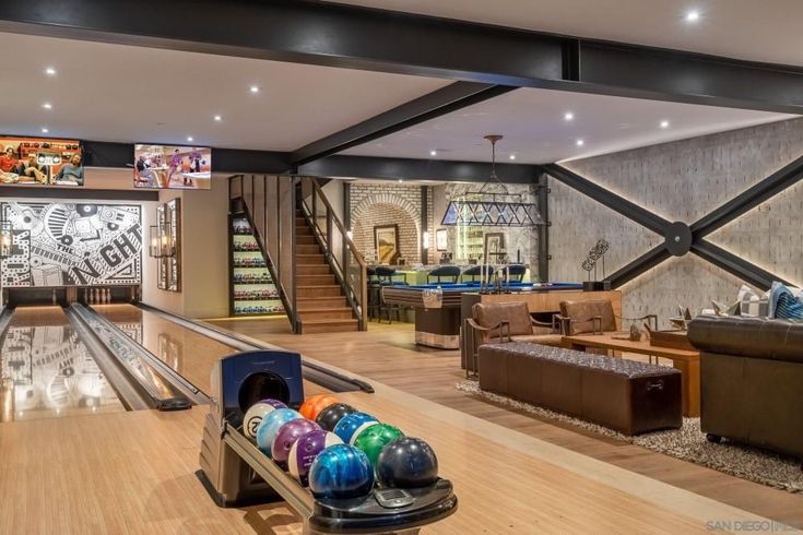 a bowling alley with several bowling balls on the table and two couches in the background