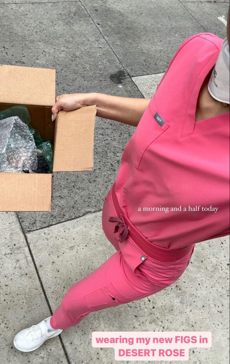 a woman in pink scrubs is holding a box with garbage inside it and the words, wearing my new figs in desert rose