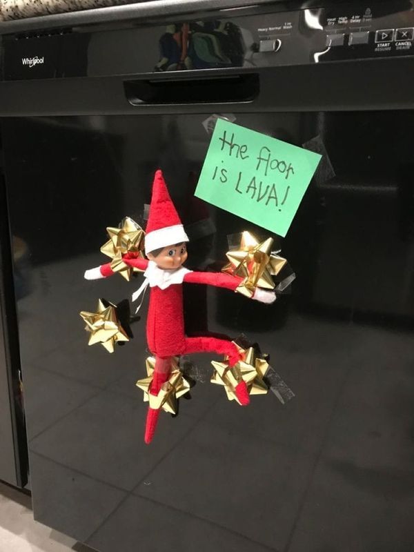 an elf is hanging on the front of a dishwasher with gold stars around it