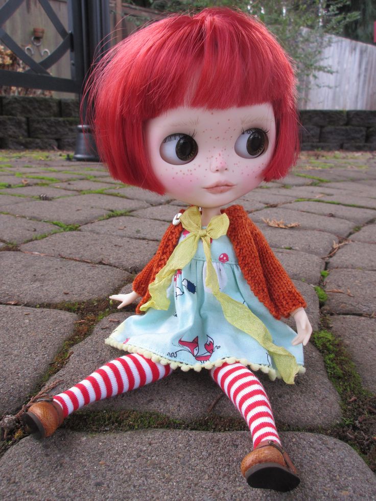 a doll with red hair sitting on the ground