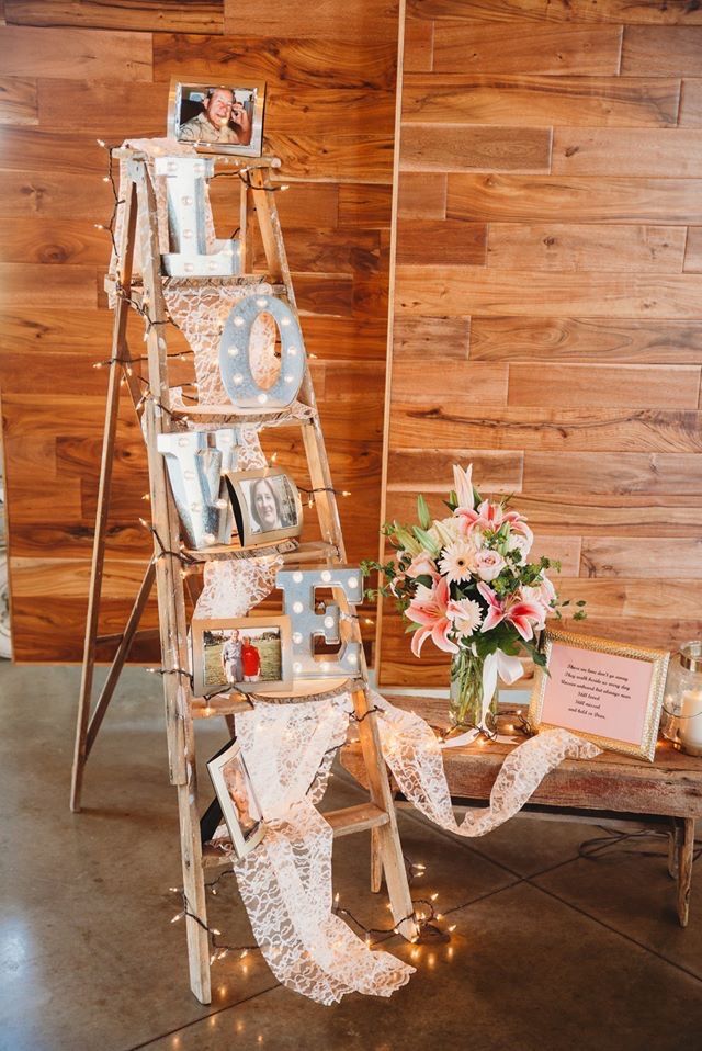 a ladder decorated with photos and lights for a rustic wedding at the barn on main street