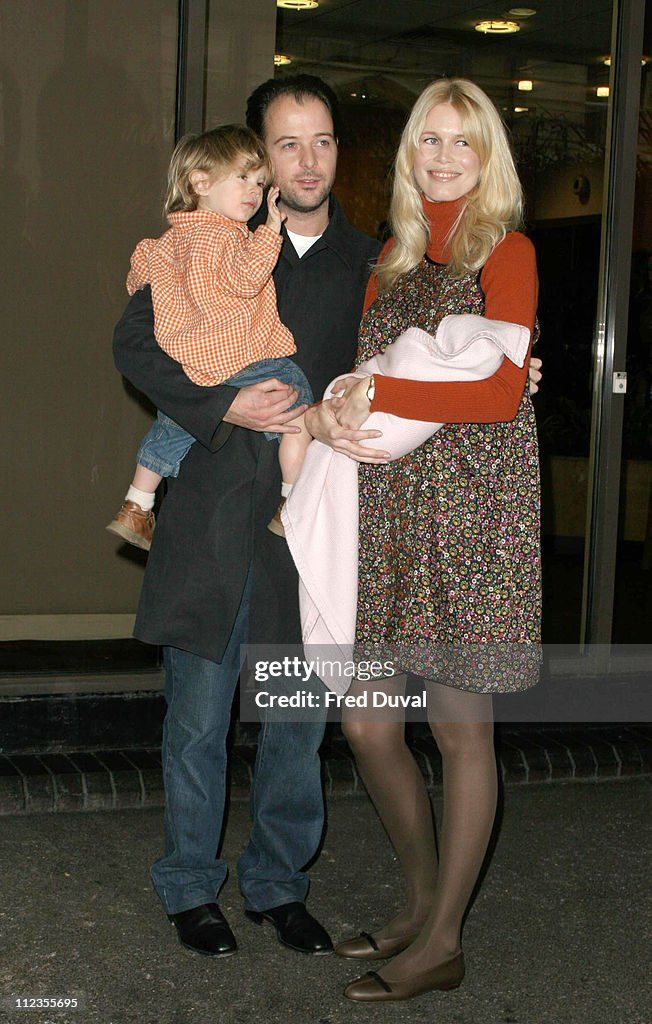 a man and woman holding a baby in their arms while standing next to each other