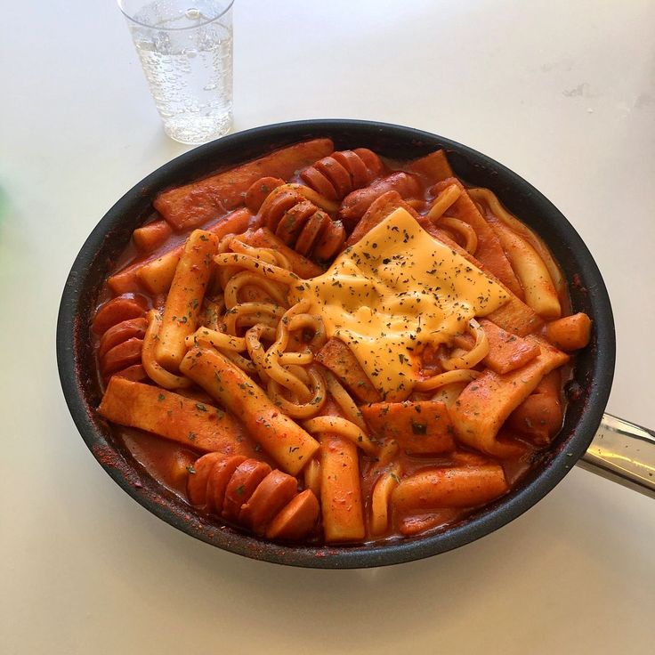 a skillet filled with pasta and sauce on top of a table