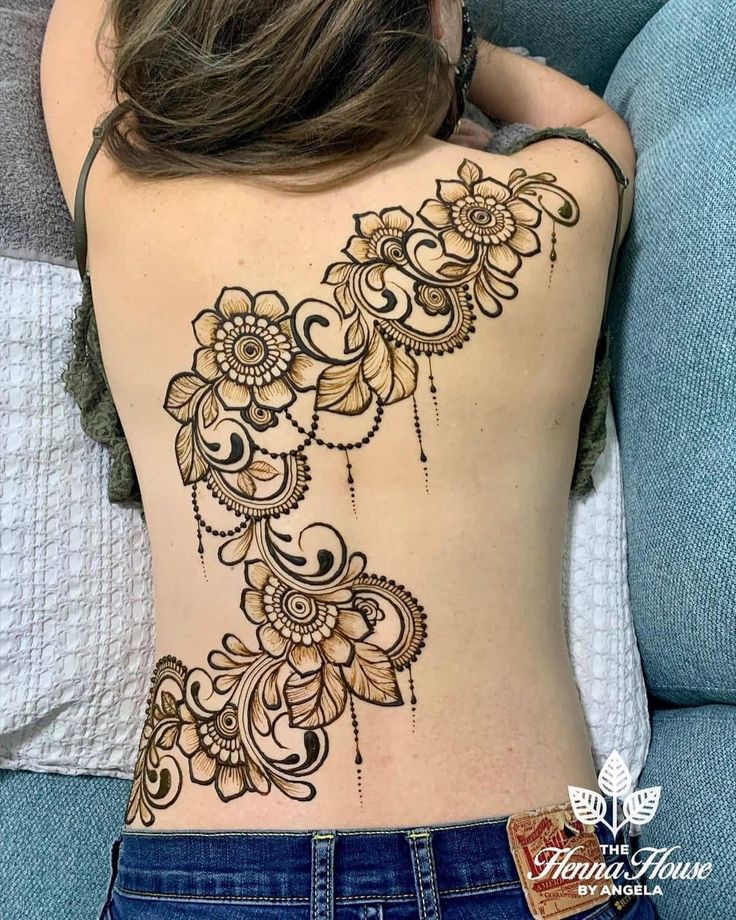 the back of a woman's body with henna tattoos on it