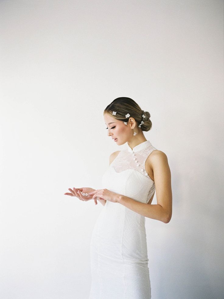 a woman in a white dress is holding her hands out and looking down at something