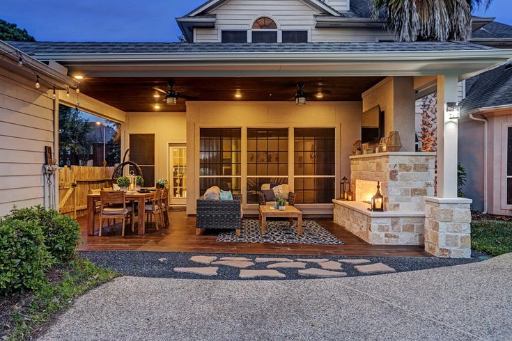 an outdoor living area with patio furniture and lighting on the front porch at night time