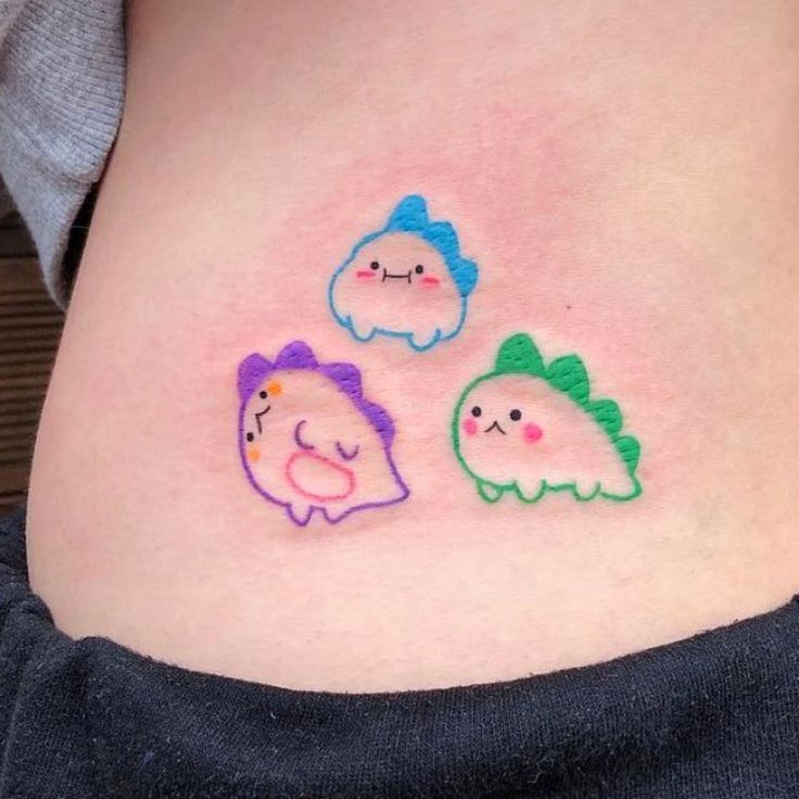 three little fish tattoos on the side of a woman's stomach, one is drawn with colored pencils