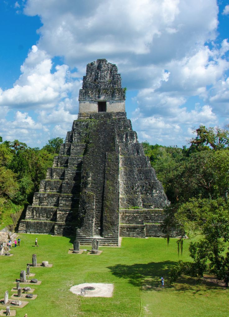 an ancient structure in the middle of a green field