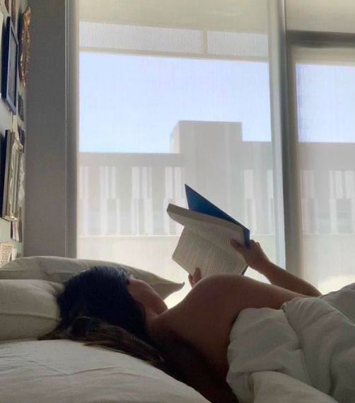 a woman laying in bed reading a book