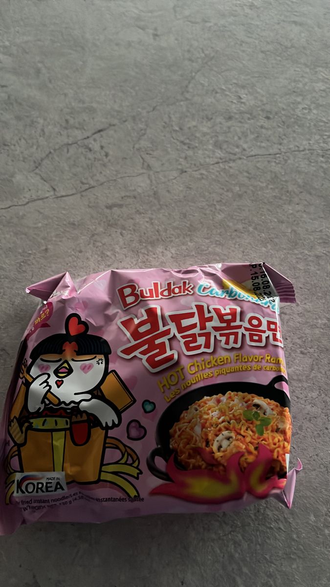 a bag of noodles with hello kitty on the side sitting on the ground next to a fork