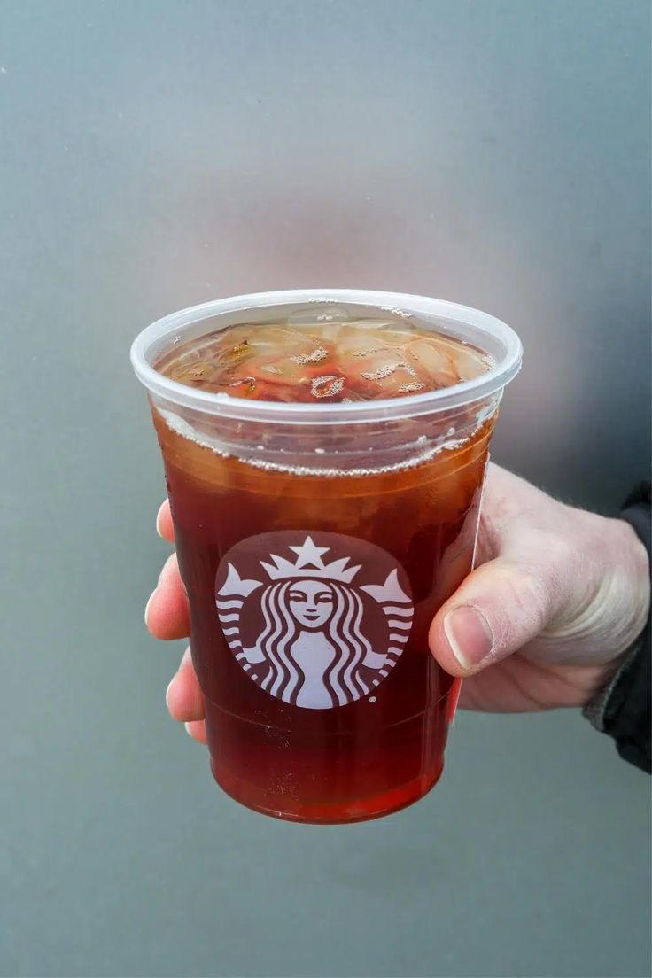 a person holding up a starbucks drink in their hand