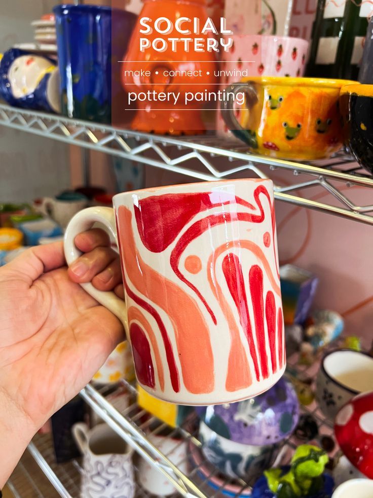 a person holding a coffee cup in front of a shelf full of mugs