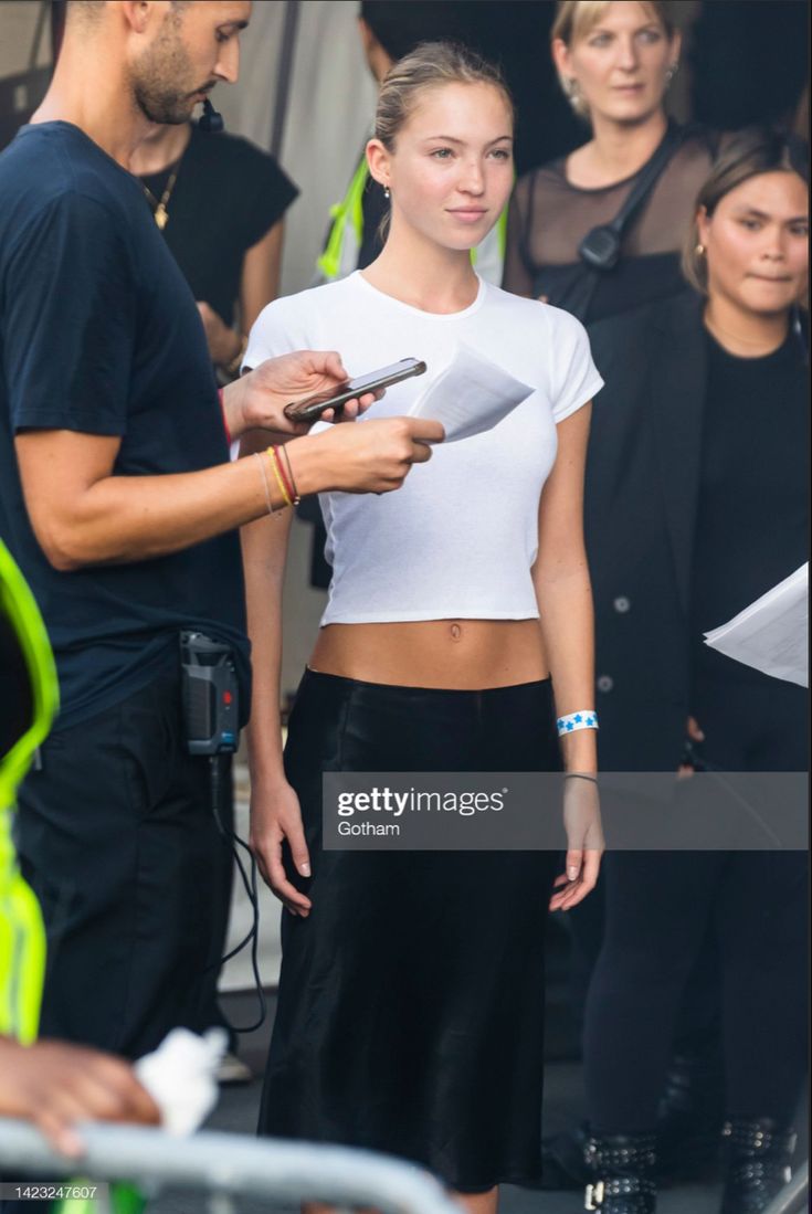 a woman in white shirt and black skirt standing next to a man holding a knife