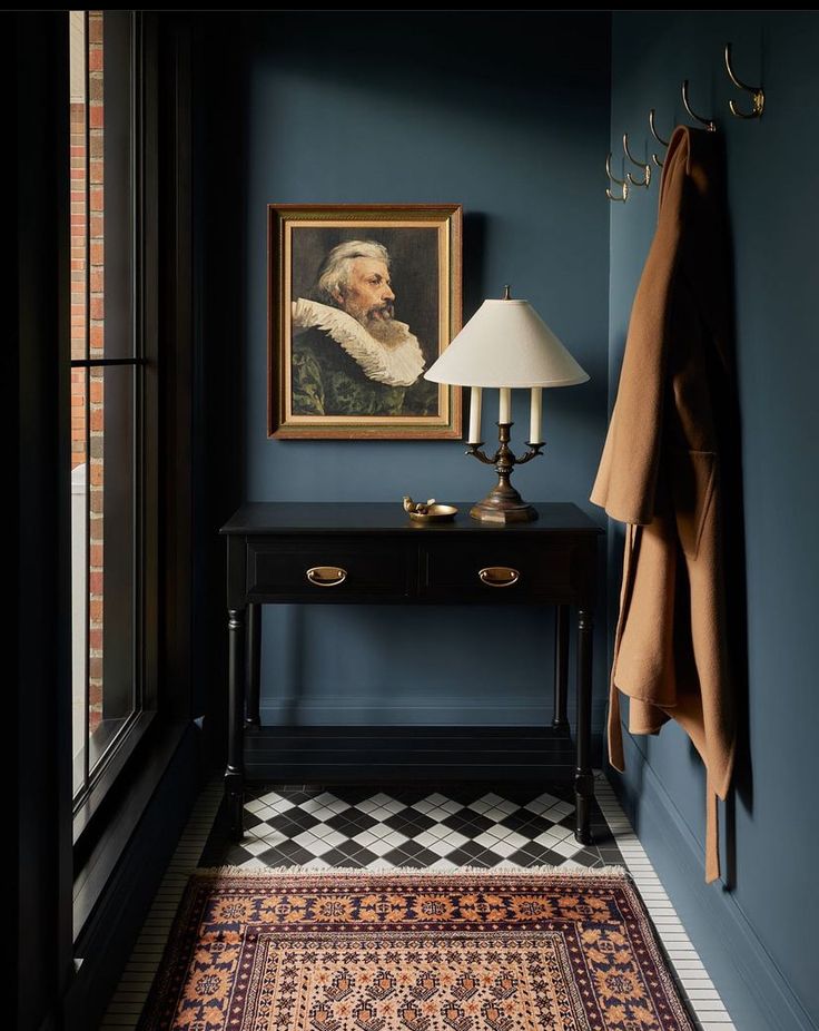 a room with blue walls and a painting on the wall next to a black table