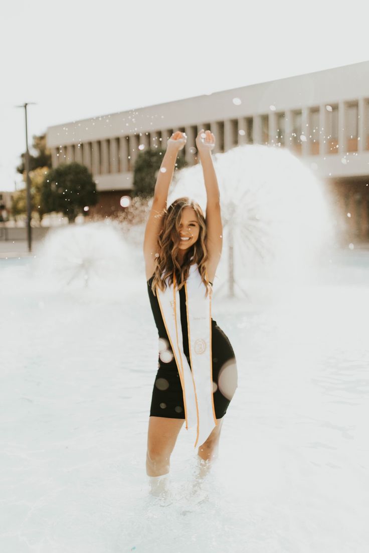 a woman in a black and white bathing suit standing in the water with her arms up