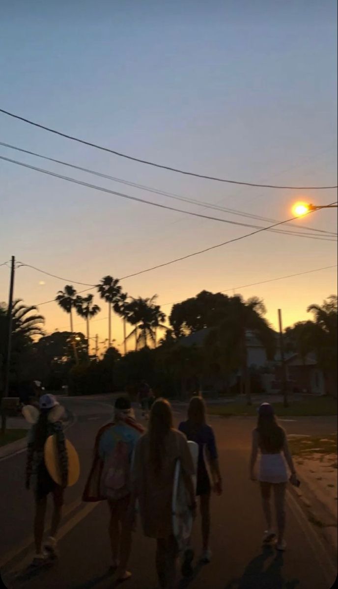 several people walking down the street at sunset