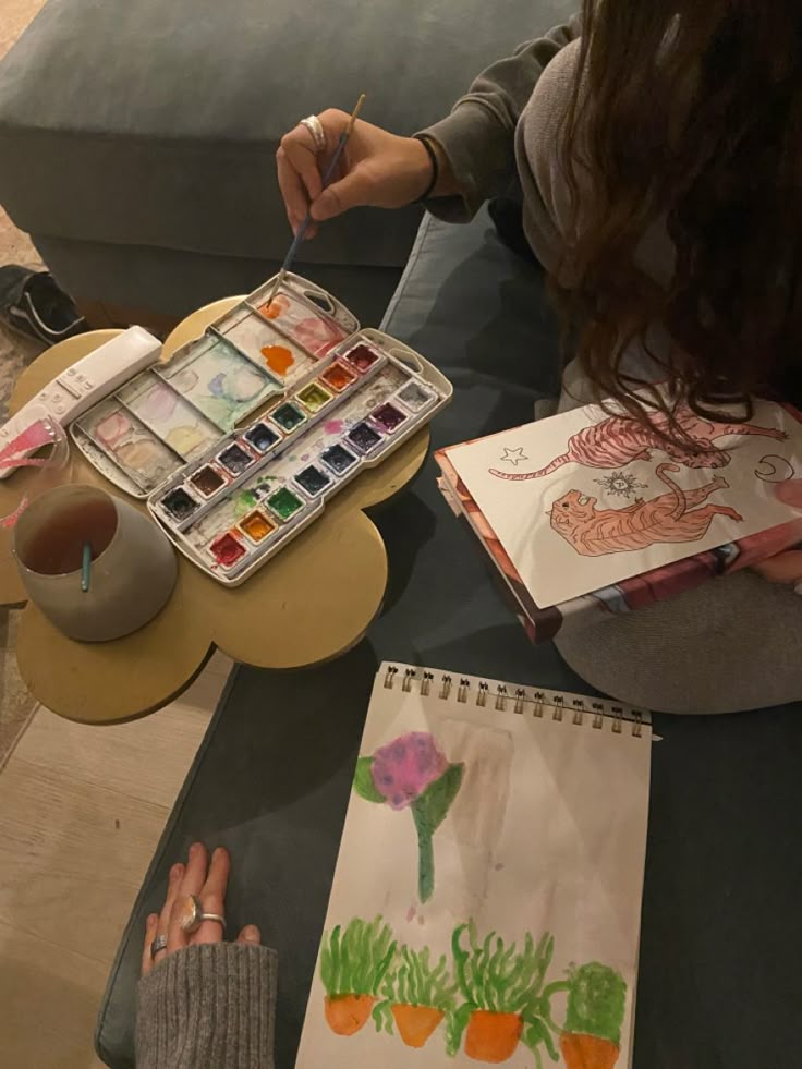 a woman sitting at a table with some art supplies