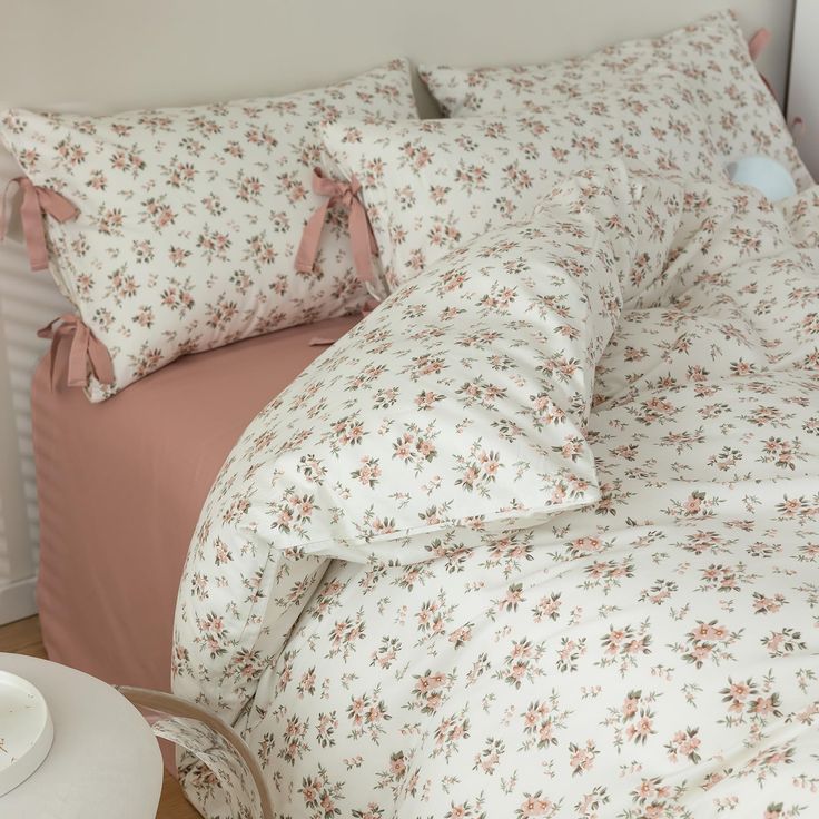 a bed with floral sheets and pillows on top of it next to a night stand