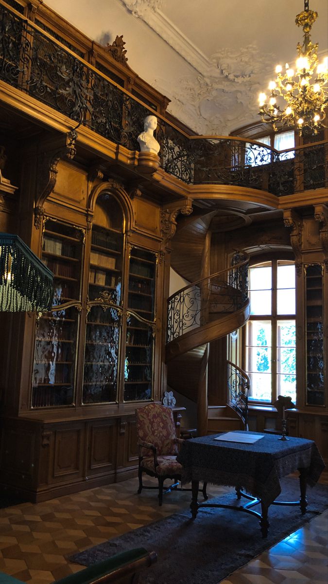 a room with many bookshelves and chandeliers on the ceiling, along with a piano