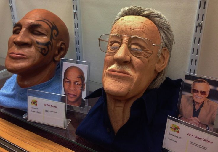 two heads with faces painted on them are sitting in front of a mirror, one is wearing glasses and the other has his face painted