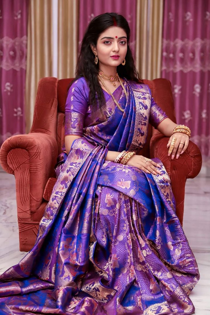 a woman sitting in a chair wearing a purple sari