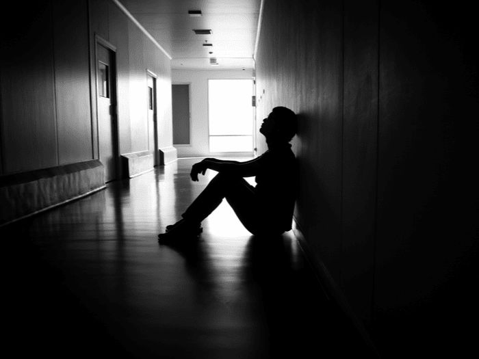 a man sitting on the floor in an empty hallway with his feet up against the wall