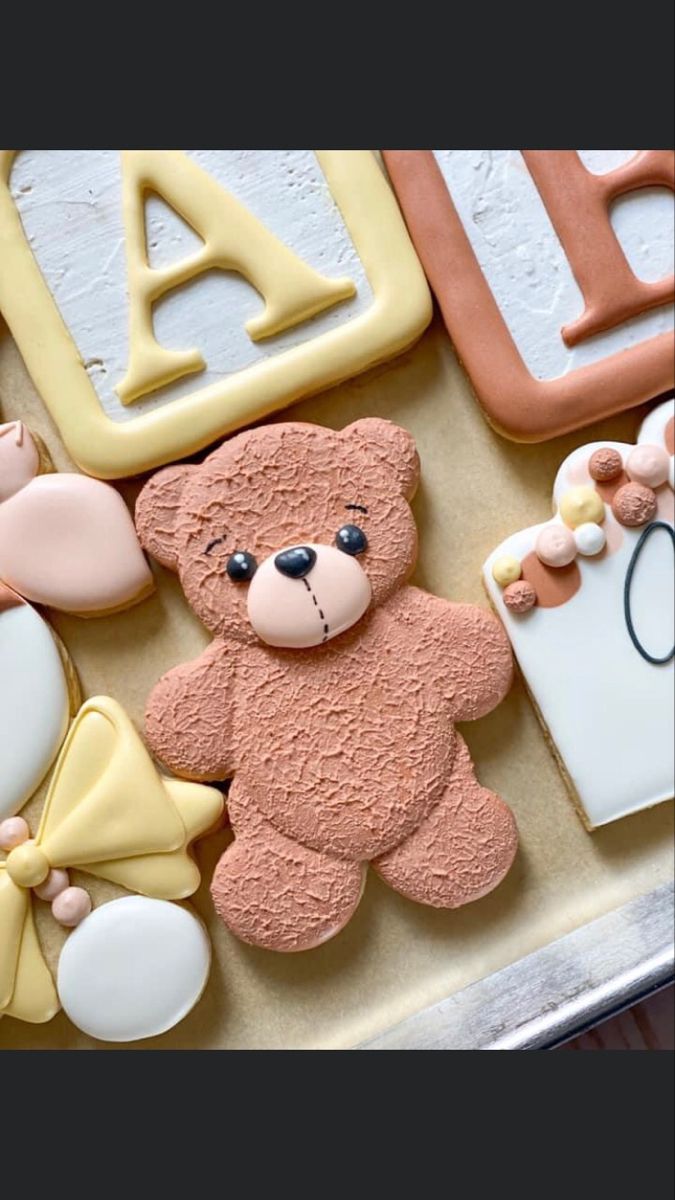 decorated cookies in the shape of teddy bears and other items on a baking sheet with icing