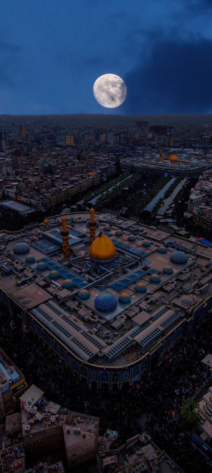 an aerial view of a city at night with the moon in the background