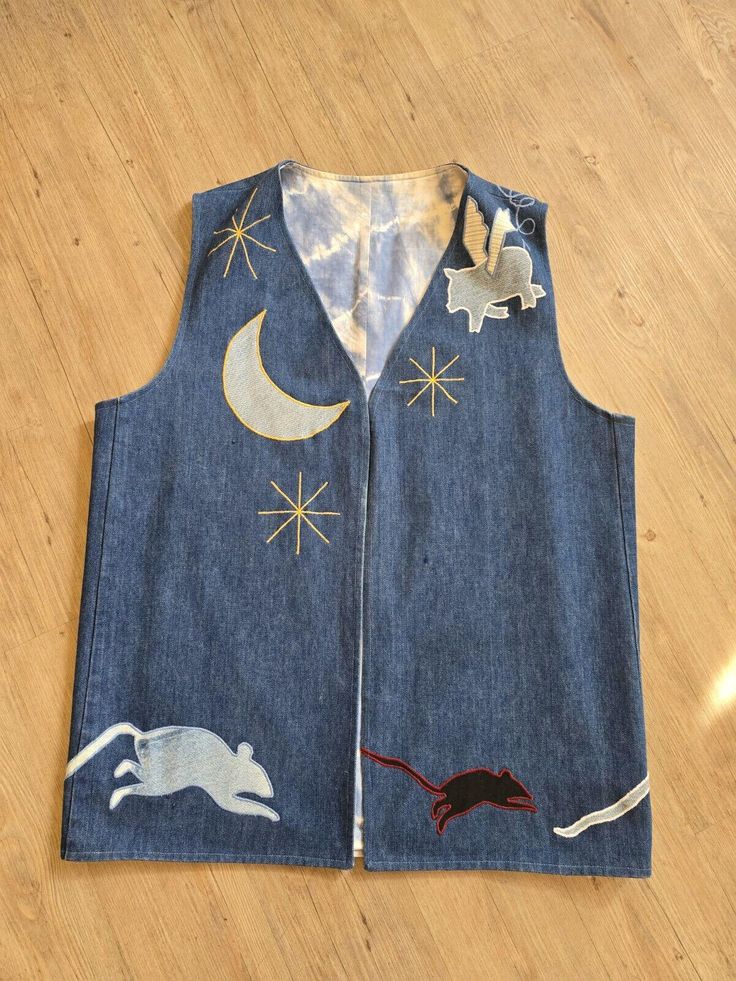 an old jean vest with cats and stars on the side, sitting on a wooden floor