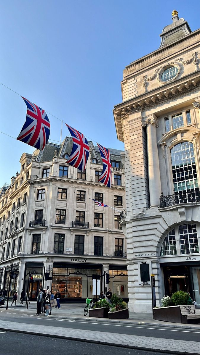 the british flag is flying in front of an old building with two flags on it's roof