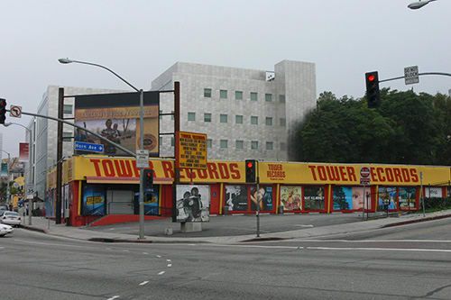 an intersection with traffic lights and storefronts on the corner in front of buildings