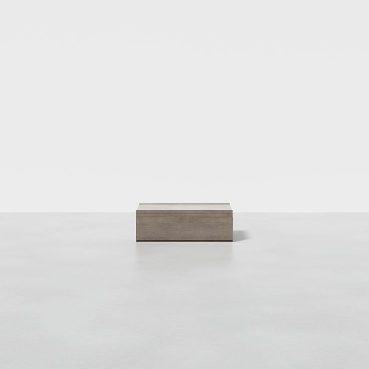 a square object sitting on top of a white floor in front of a gray wall