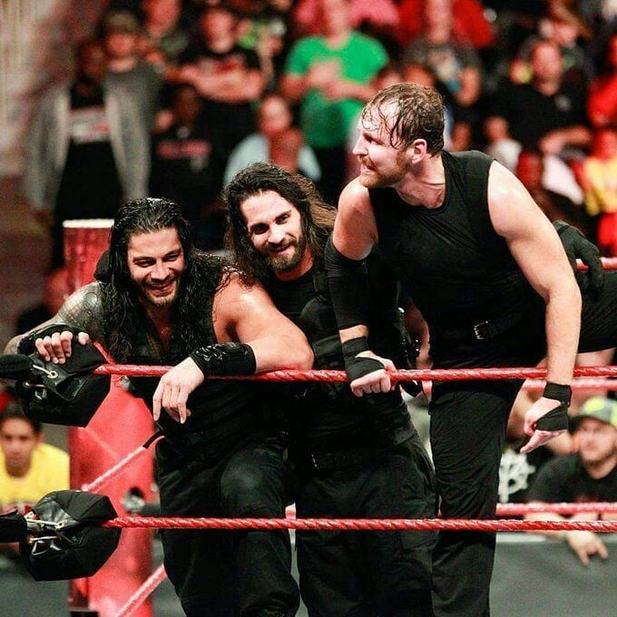 three men standing on top of a wrestling ring