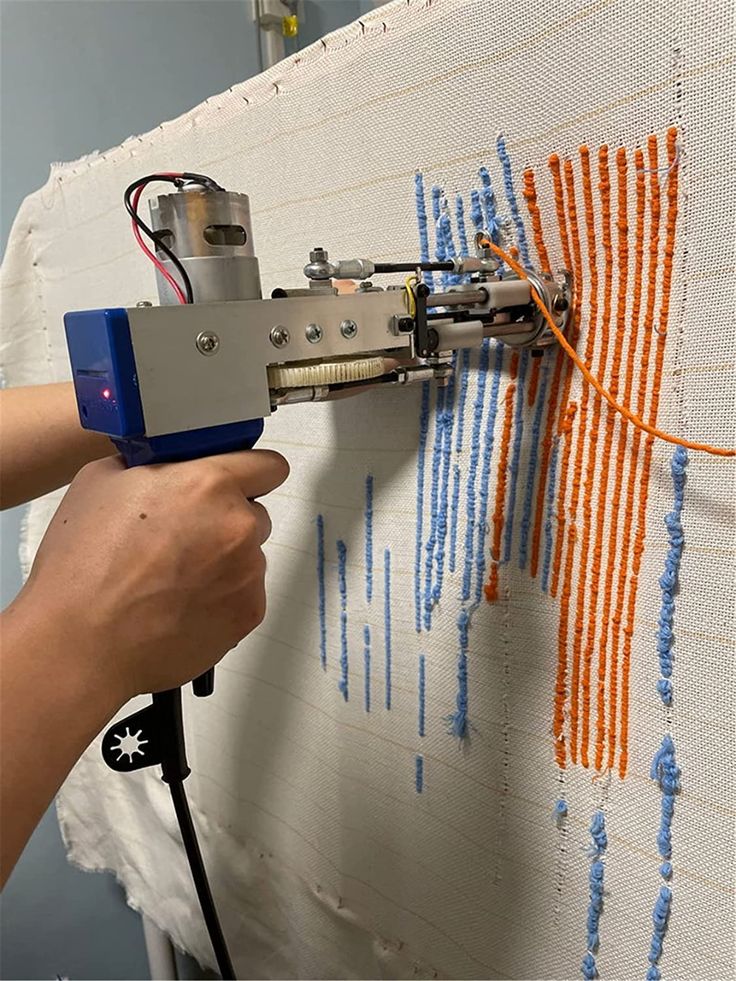 a person is using a machine to make an art work on a wall with orange and blue lines