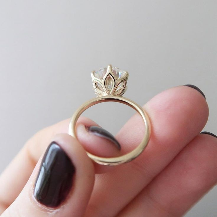 a woman's hand holding a ring with a flower on it