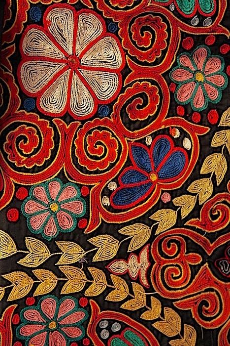 an intricately decorated cloth with flowers and leaves on the side, is shown in red