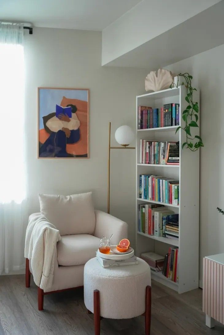 a living room with a white chair and bookshelf