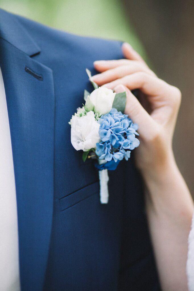 a close up of a person wearing a suit and holding a boutonniere