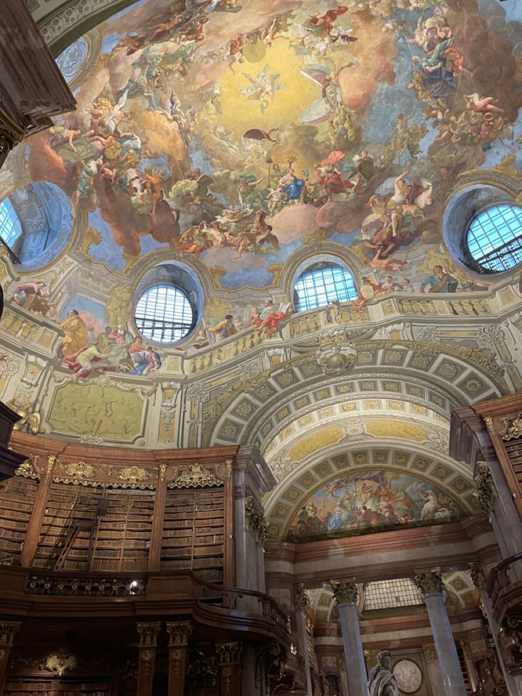 the interior of a library with many bookshelves and paintings on the ceiling