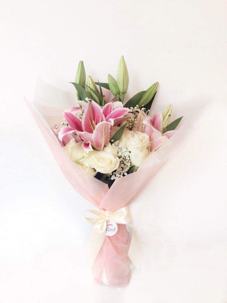 a bouquet of pink and white flowers on a white background with a ribbon tied around it