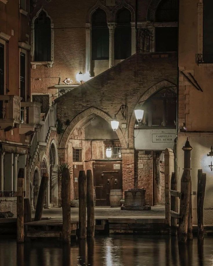 an old building sitting next to a body of water in the middle of town at night