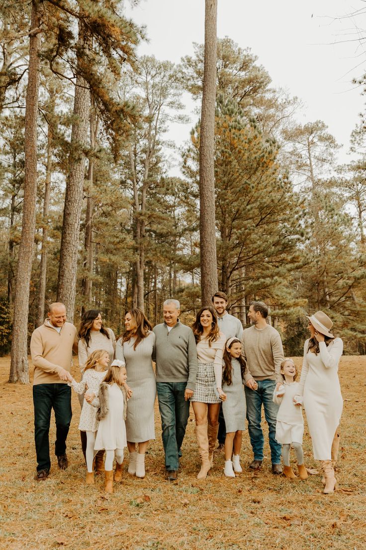 an extended family poses for a photo in the woods with tall pine trees behind them