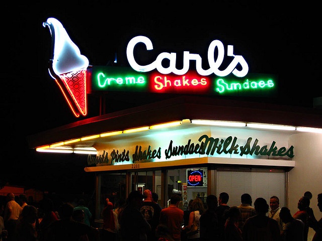 a group of people standing outside of a restaurant at night