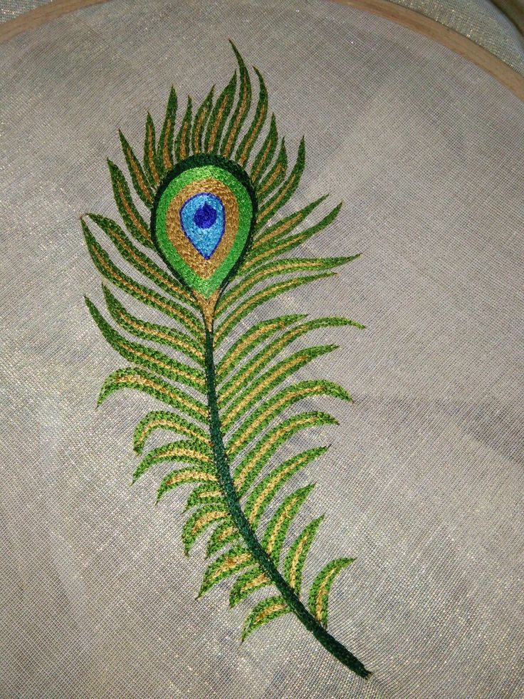 an embroidered peacock feather with green leaves on it