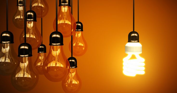 several light bulbs hanging from the ceiling in an orange room with one bulb turned on