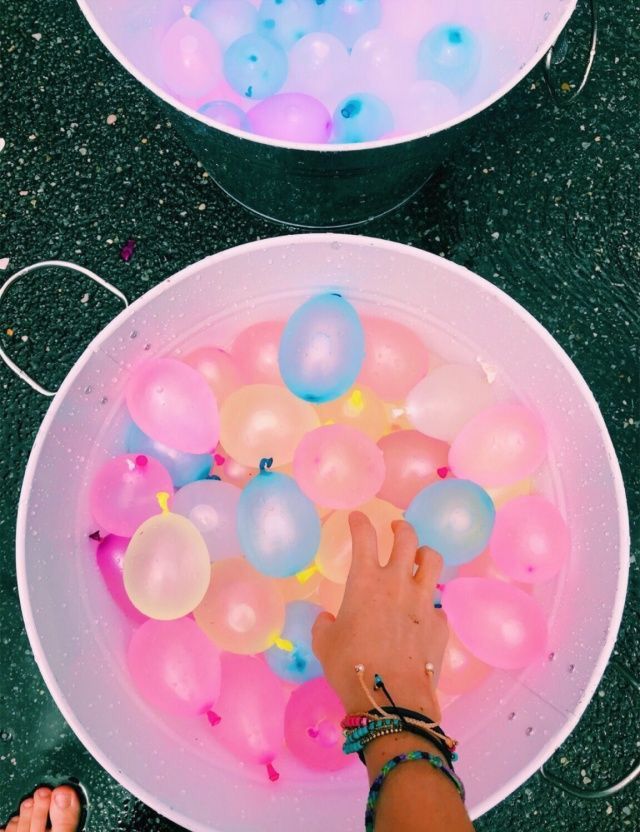 two bowls with balloons floating in them and someone's hand reaching for the bowl