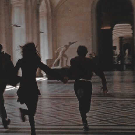 three people are running in the middle of a room with marble flooring and columns